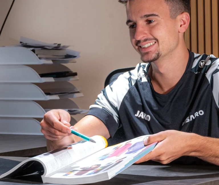 Mitarbeiter wählt am Besprechungstisch mit dem Stift ein Motiv aus einem Katalog aus