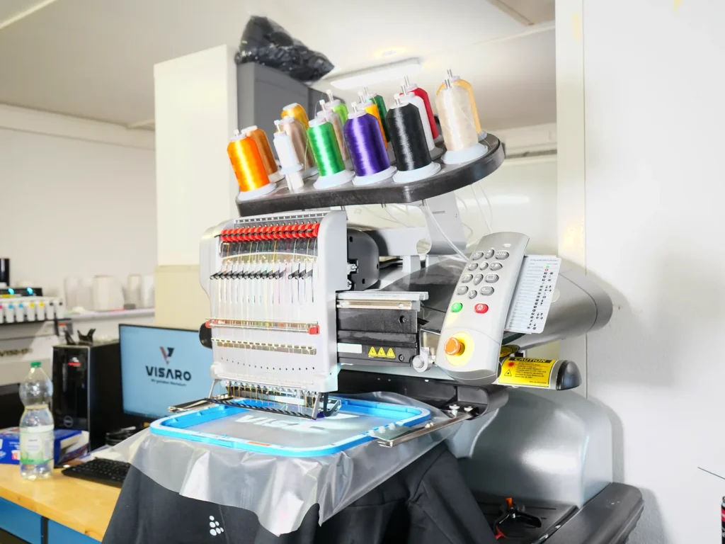Stickmaschine mit bunten Garnrollen im Stickatelier