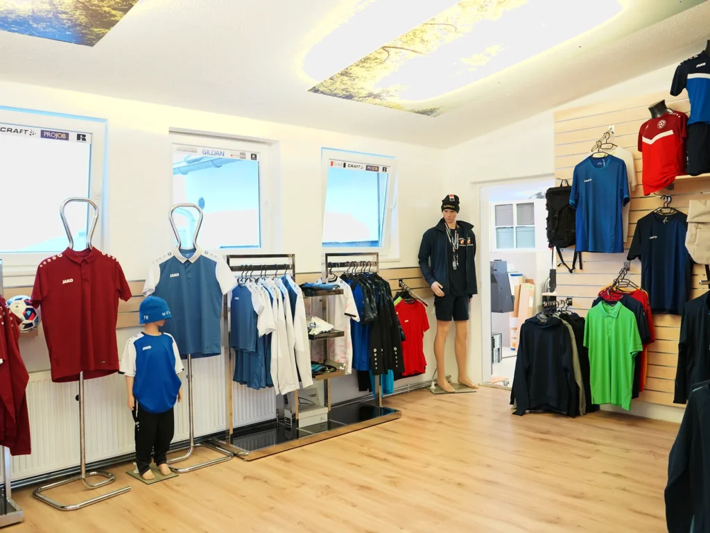 Blick in den Schauraum mit Shirts, Jacken und Trainingsbekleidung auf Ständern