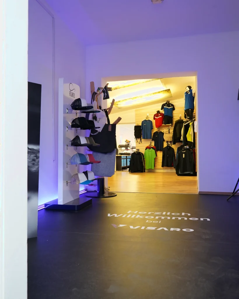 Schauraum mit Bekleidung, am Boden die Projektion „Herzlich willkommen bei VISARO“
