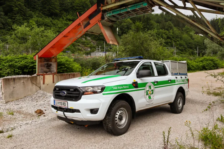 Weißer Pick-up mit grüner Beschriftung der Bergrettung im Gelände