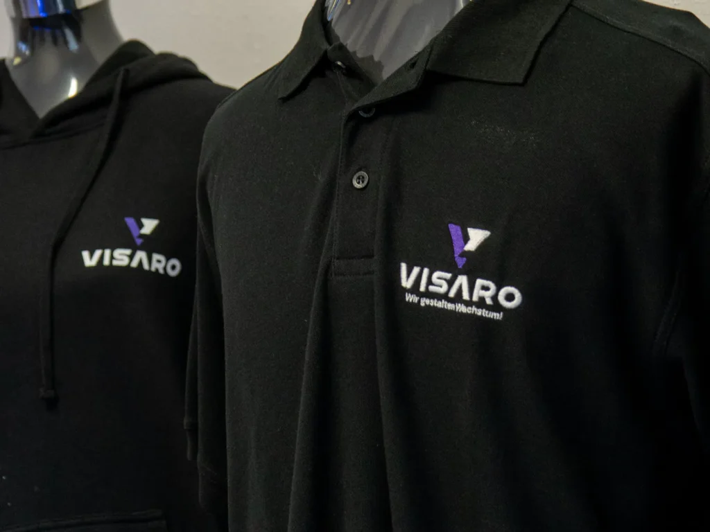Schwarzes Poloshirt und Hoodie mit VISARO Logo auf Büsten