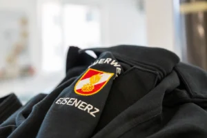 Gestickte Feuerwehrmarke „Eisenerz“ auf einem dunklen Kapuzenpullover