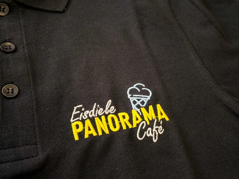 Schwarzes Poloshirt mit gesticktem Café-Logo in Gelb und Weiß