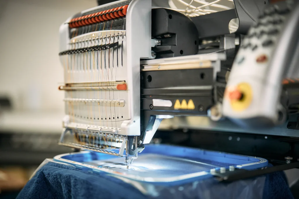 Stickmaschine stickt auf ein dunkelblaues Textil
