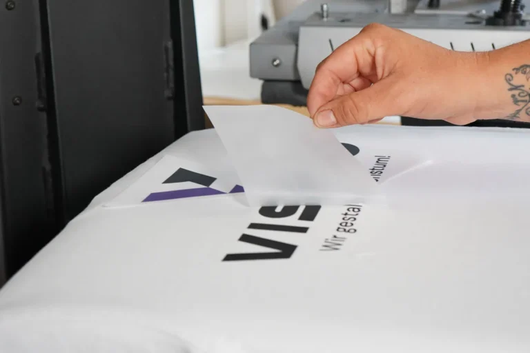 Trägerfolie wird nach dem Pressen von einem bedruckten weißen Shirt abgezogen
